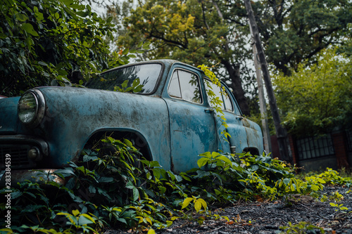 Abandoned rusty car in junkyard. Forgotten discarded rusty old blue car in scrapyard