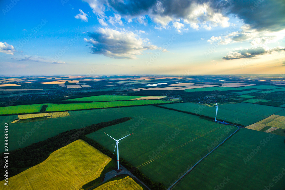 wind generators among the fields at sunset. Windmills by the countryside. New technology. Renewable energy. shot on a drone 