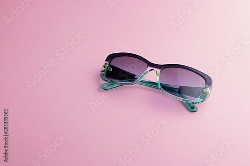 Fashionable rectangular sunglasses with gradient tints closeup on pink background