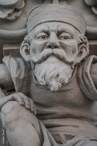 Sculpture of an old small and bearded funny man, dwarf, as an atlant in downtown of Magdeburg, Germany, closeup, details