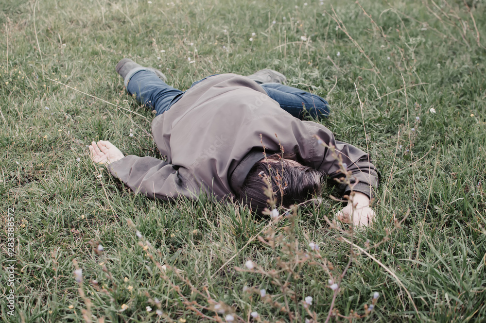 The corpse of a tramp in the grass. Criminal. Alcoholic intoxication. Killing a homeless man. dead body after lightning strike The corpse of a tramp in the grass. Criminal. Alcoholic intoxication. Killing a homeless man. dead body after lightning strike