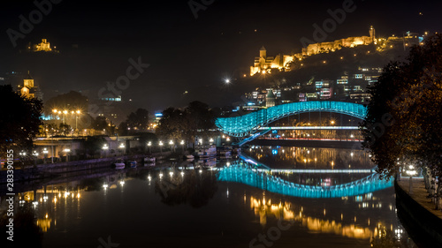 Pedestrian bridge of peace over the Mtkvari  Kura  River in Tbilisi at night. Narikala fortress.