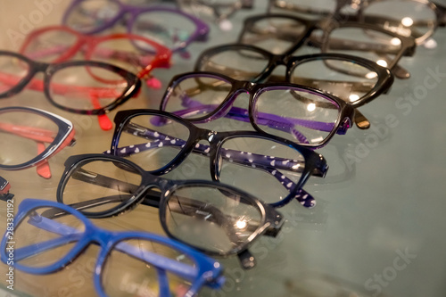 exhibitor of glasses consisting of shelves of fashionable glasses shown on a wall at the optical shop. Colorful Elegant eyeglasses in a store.Selective focus