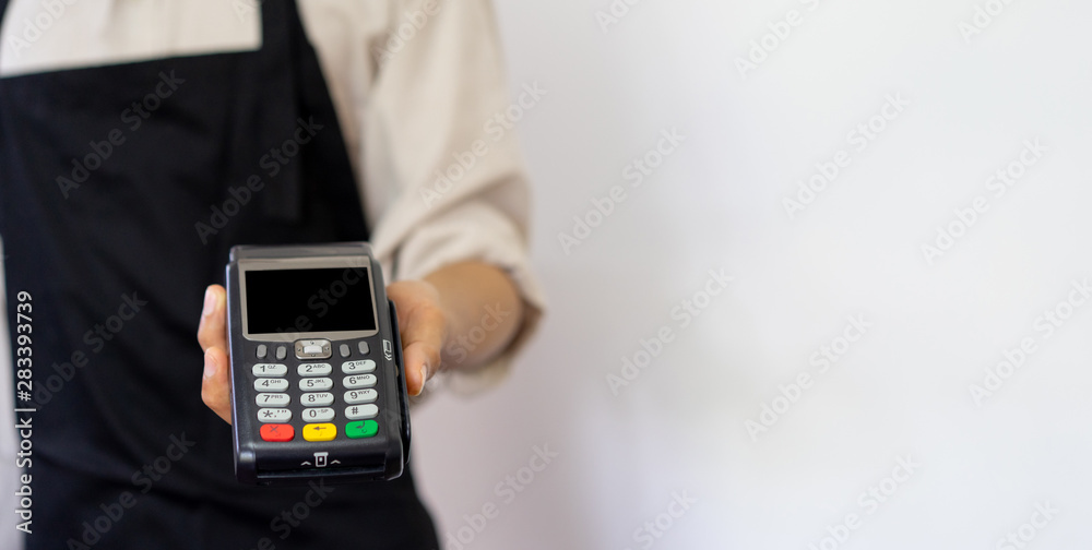 close up business owner man hand showing a electronic banking money machine for receiving purchase from customer in the shop , business and technology of contactless payment concept close up business owner man hand showing a electronic banking money machine for receiving purchase from customer in the shop , business and technology of contactless payment concept