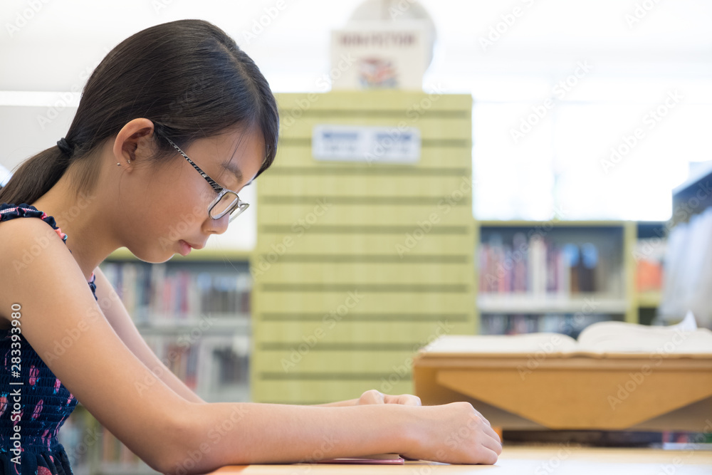 Φωτογραφία Portrait of young Asian girl reading book in library