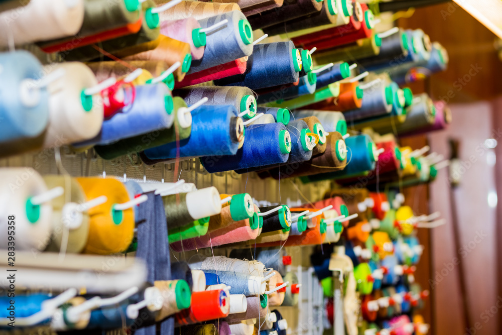 variety big and used spools of colorful sewing threads. Tailor shop theme background, Textiles and clothing industry concept. selective focus.Colorful thread spools used in fabric and textile industry