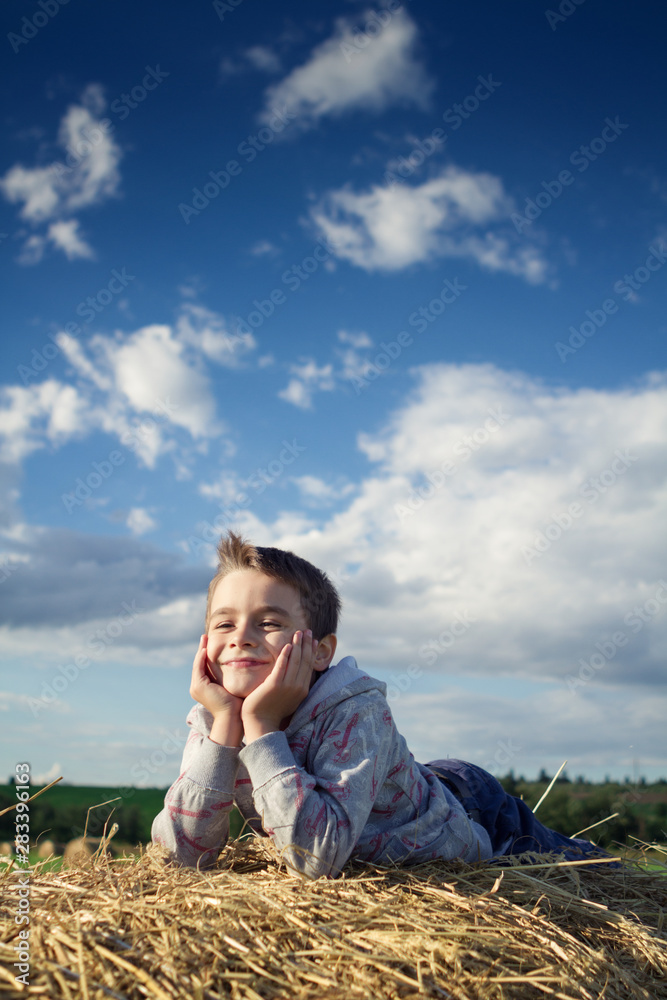 the boy lies in the hay in the summer