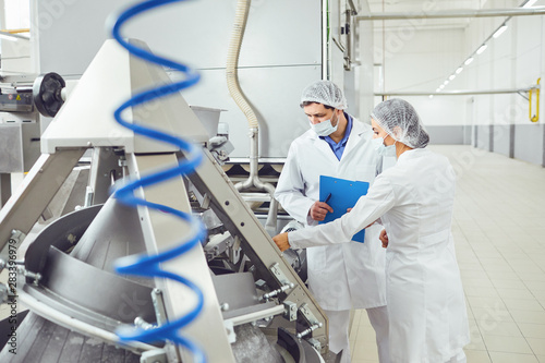 Technologists inspector in masks at food factory.