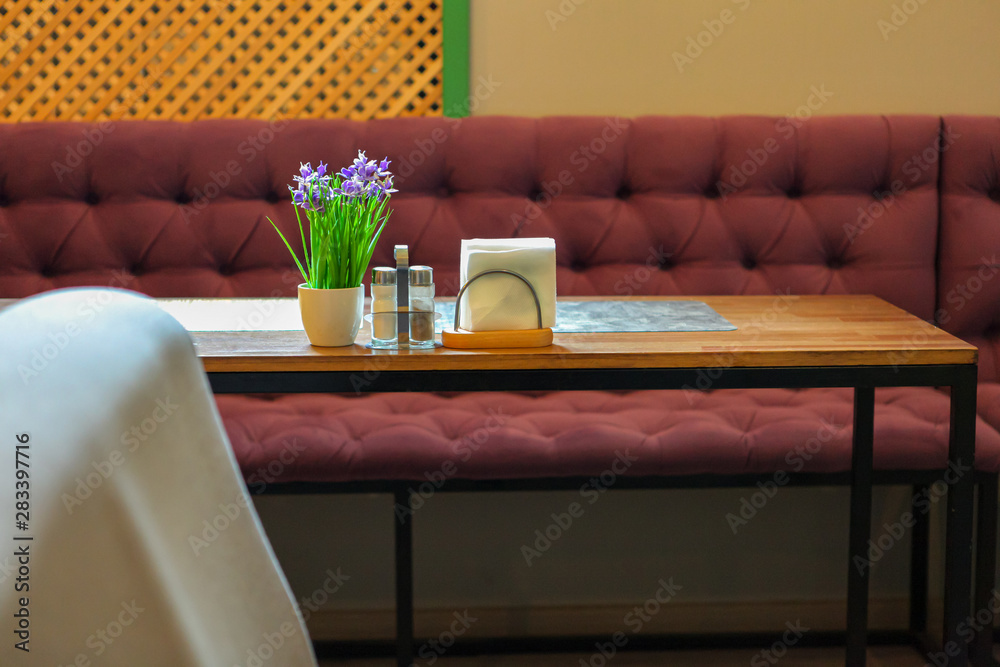 Empty table with a set of napkins and spices: salt and pepper next to a bouquet of flowers. Restaurant serving on the table with napkin holder. A table for two visitors. Free space for text.