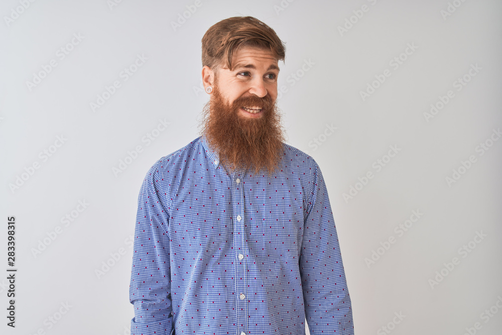 Young redhead irish man wearing casual shirt standing over isolated white background looking away to side with smile on face, natural expression. Laughing confident. Young redhead irish man wearing casual shirt standing over isolated white background looking away to side with smile on face, natural expression. Laughing confident.