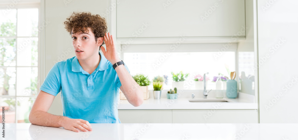 Wide shot of young handsome man at home smiling with hand over ear listening an hearing to rumor or gossip. Deafness concept. Wide shot of young handsome man at home smiling with hand over ear listening an hearing to rumor or gossip. Deafness concept.