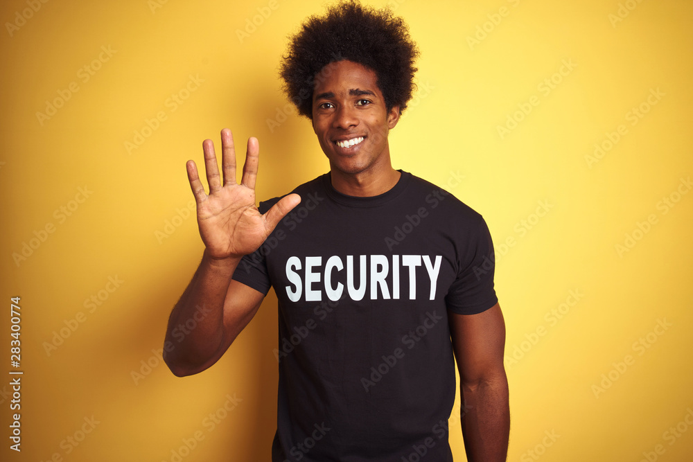 American safeguard man with afro hair wearing security uniform over isolated yellow background showing and pointing up with fingers number five while smiling confident and happy. American safeguard man with afro hair wearing security uniform over isolated yellow background showing and pointing up with fingers number five while smiling confident and happy.