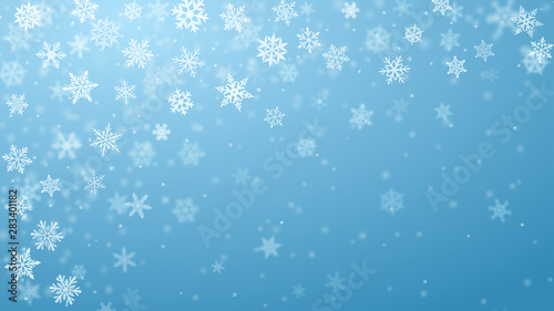 Christmas background of complex blurred and clear falling snowflakes in light blue colors with bokeh effect
