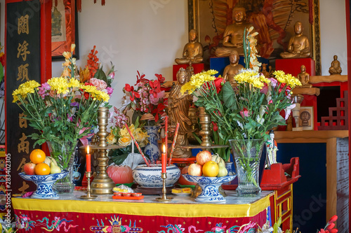 Interior of a vietnamese temple in france, open to public, with statues, offerings and objects of worship.