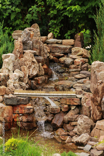 Miniature artificial stone waterfall with a bridge