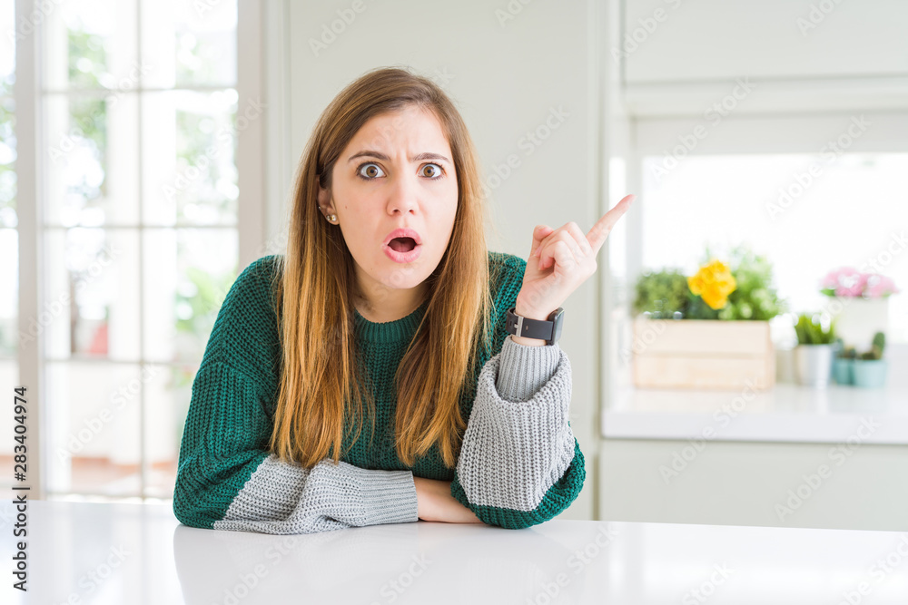 Young beautiful plus size woman wearing casual striped sweater Surprised pointing with finger to the side, open mouth amazed expression.