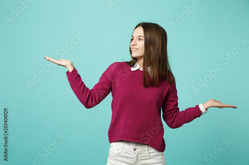 Young brunette woman girl in casual clothes posing isolated on blue green turquoise wall background studio portrait. People sincere emotions lifestyle concept. Mock up copy space. spreading hands