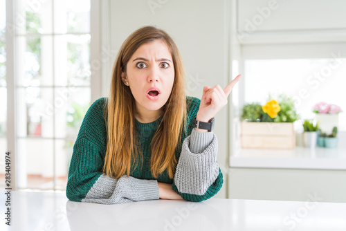 Young beautiful plus size woman wearing casual striped sweater Surprised pointing with finger to the side  open mouth amazed expression.
