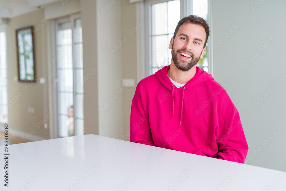 Handsome man wearing casual sweatshirt at home and smiling positive