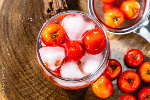 Acerola juice and Acerola fruit in a sieve and wooden background