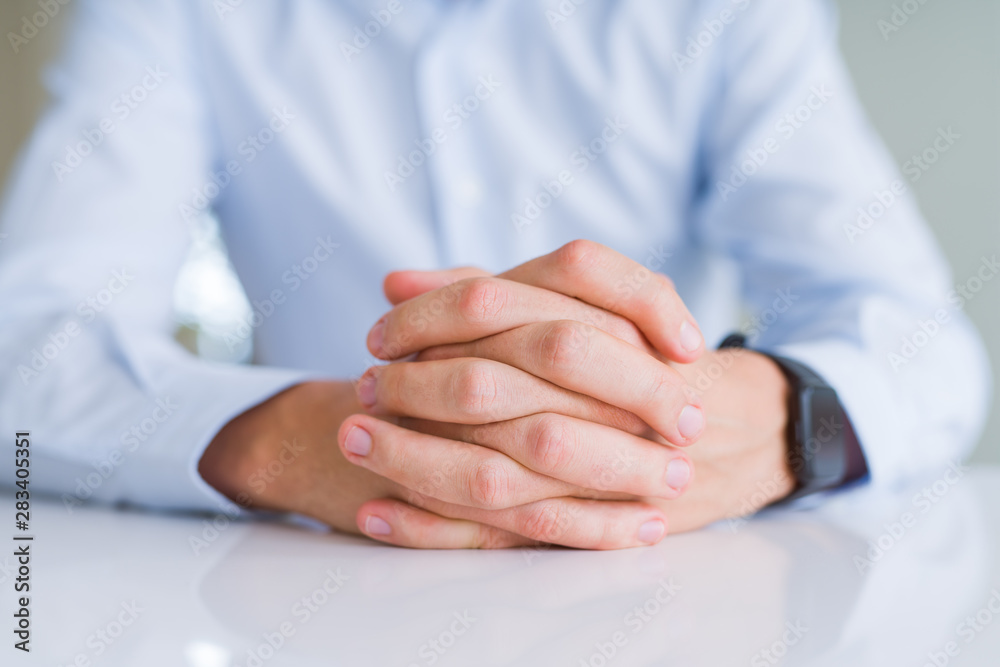 Fototapeta premium Close up of man crossed hands over white table