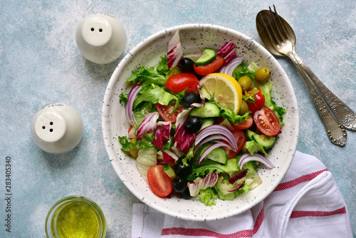 Vegetable salad with tomato, cucumber olives and lettuce. Top view with copy space.