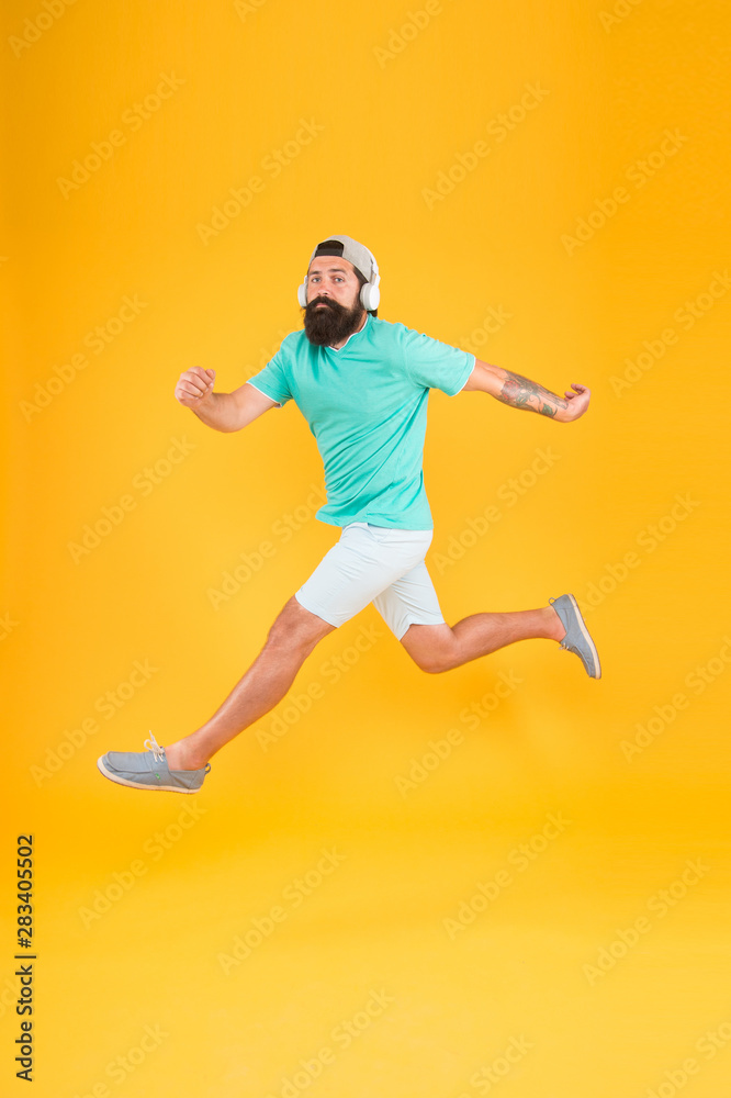 Great music for dancing. Dancer man moving to music on yellow background. Bearded man enjoy jump dancing to modern music. Energetic hipster dancing with pleasure. Listening to dancing music