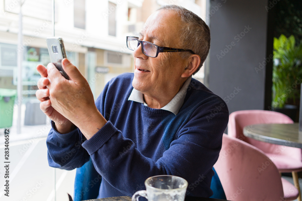 Handsome middle age senior man drinking coffee at restaurante, smiling happy enjoying and relaxing retirement using smartphone Handsome middle age senior man drinking coffee at restaurante, smiling happy enjoying and relaxing retirement using smartphone