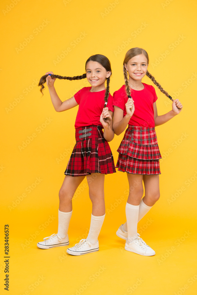 Playful kids. Happy together. School friends having fun together. Cheerful friends. Cute little girls smiling yellow background. Happy small girls wearing same outfits. Friends enjoying friendship Playful kids. Happy together. School friends having fun together. Cheerful friends. Cute little girls smiling yellow background. Happy small girls wearing same outfits. Friends enjoying friendship