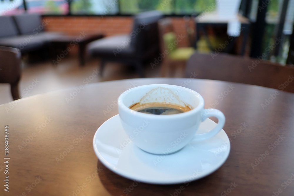 A cup of hot espresso coffee in a white cup on wooden dining table,coffee cafe background
