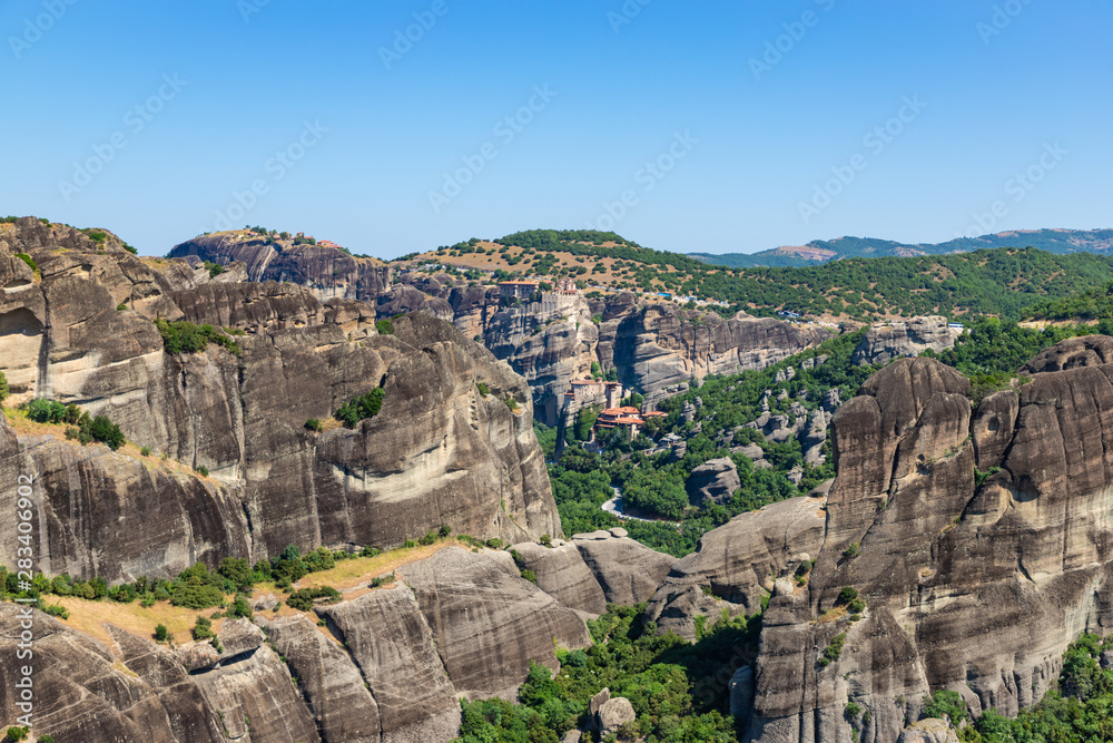 Green valley and Greek monasteries surrounded by dark cliffs, Meteora, Greece