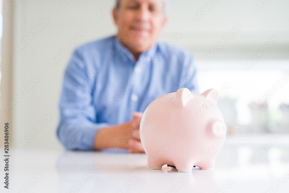 Close up of piggy bank and man smiling at the background Close up of piggy bank and man smiling at the background