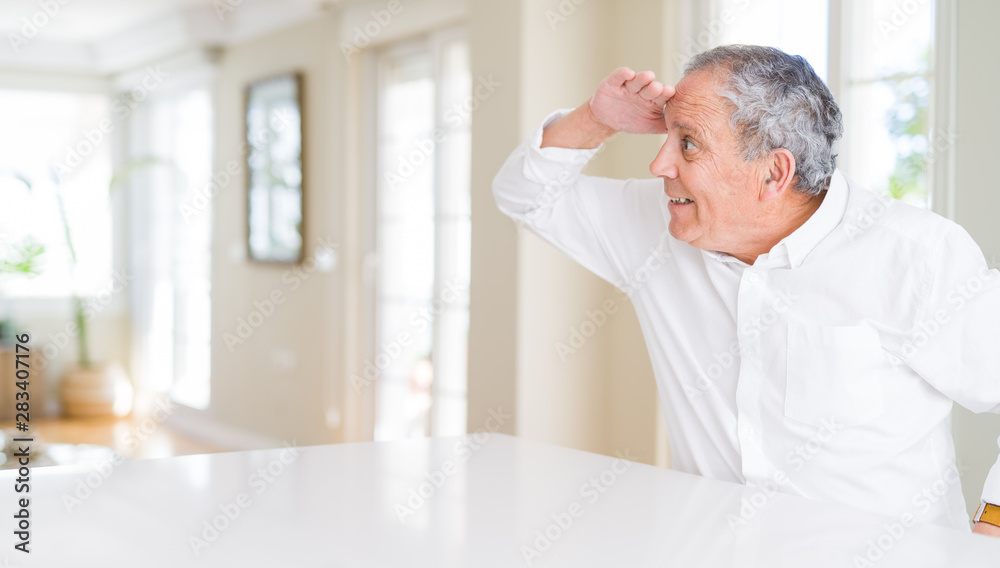 Handsome senior man at home very happy and smiling looking far away with hand over head. Searching concept. Handsome senior man at home very happy and smiling looking far away with hand over head. Searching concept.