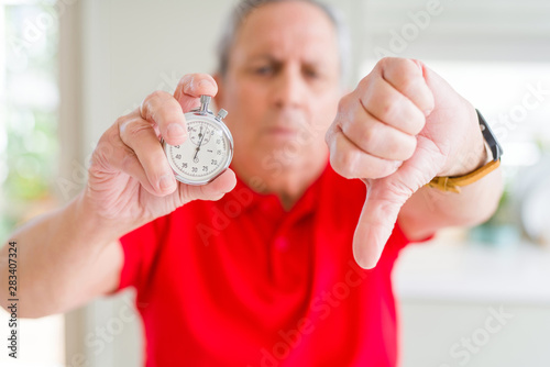 Fotografie Handsome senior man holding stopwach showing countdown with angry face, negative