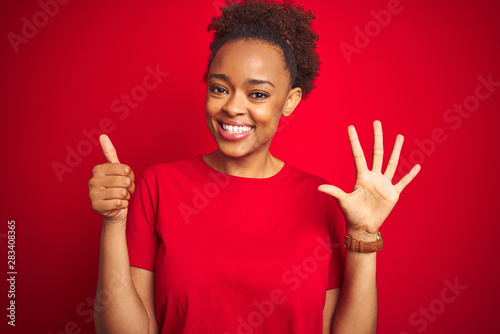 Young beautiful african american woman with afro hair over isolated red background showing and pointing up with fingers number six while smiling confident and happy.