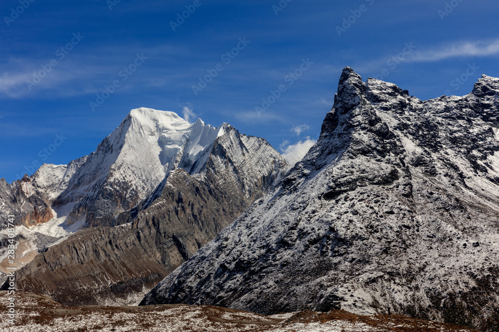 Chenadorje, holy snow mountain in Daocheng Yading Nature Reserve - Garze, Kham Tibetan Pilgrimage region of Sichuan Province China. Epic snow capped mountains, Blue Sky Background