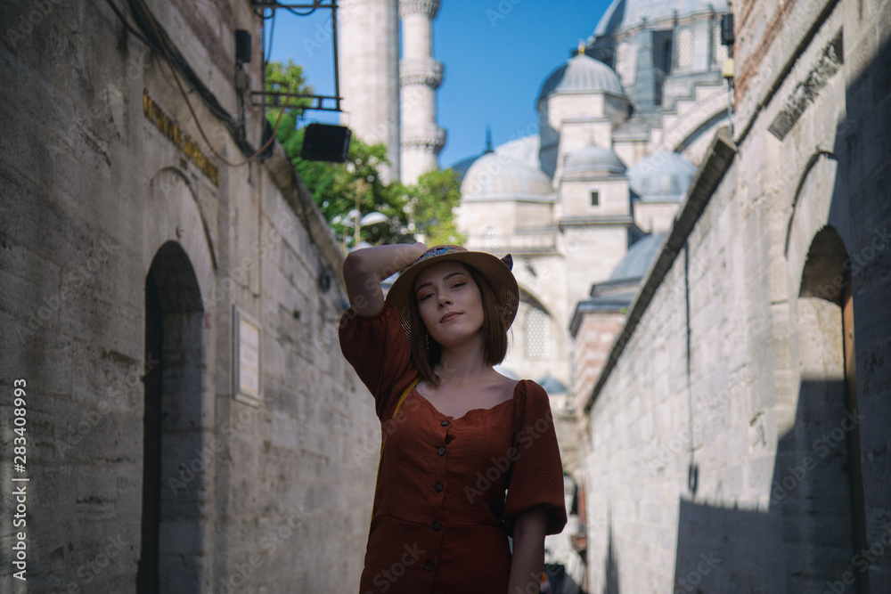 Beautiful girl with orange colored dress posing in front of the Suleymaniye Mosque