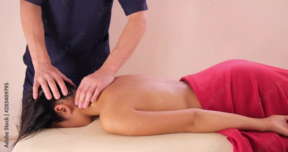 A young woman gets a massage procedure. Masseur makes back massage. A young woman gets a massage procedure. Masseur makes back massage.
