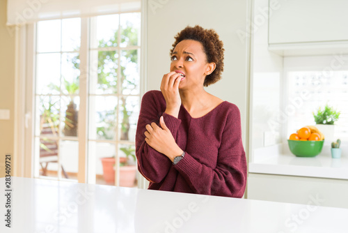 Young beautiful african american woman at home looking stressed and nervous with hands on mouth biting nails. Anxiety problem.