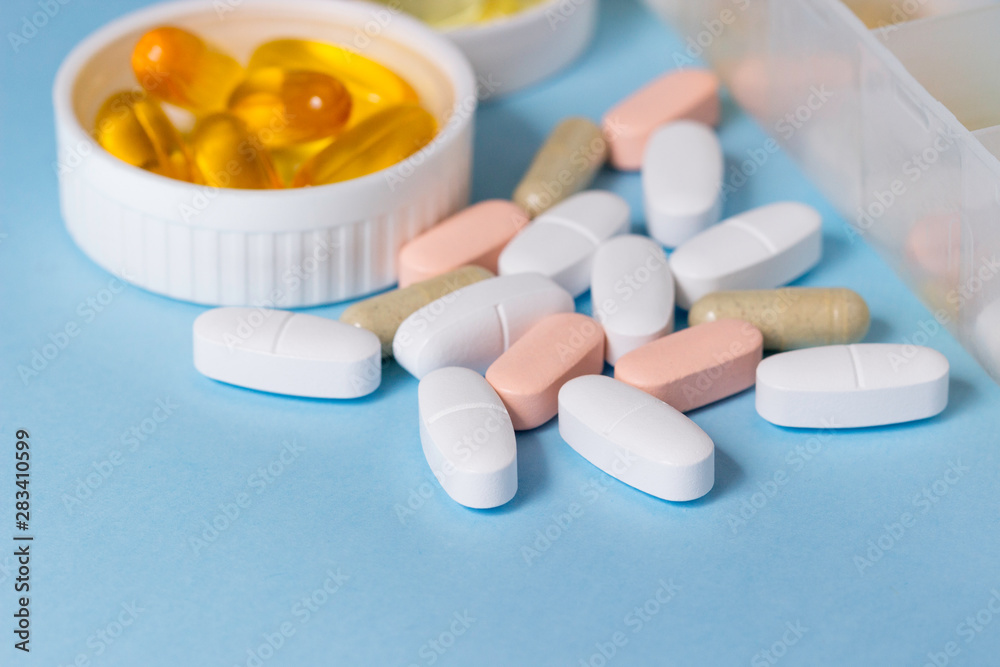 Tablets and capsules of drugs in containers and on the table.