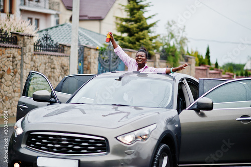 Rich business african woman in silver suv car on sunroof having fun with beer at hand.