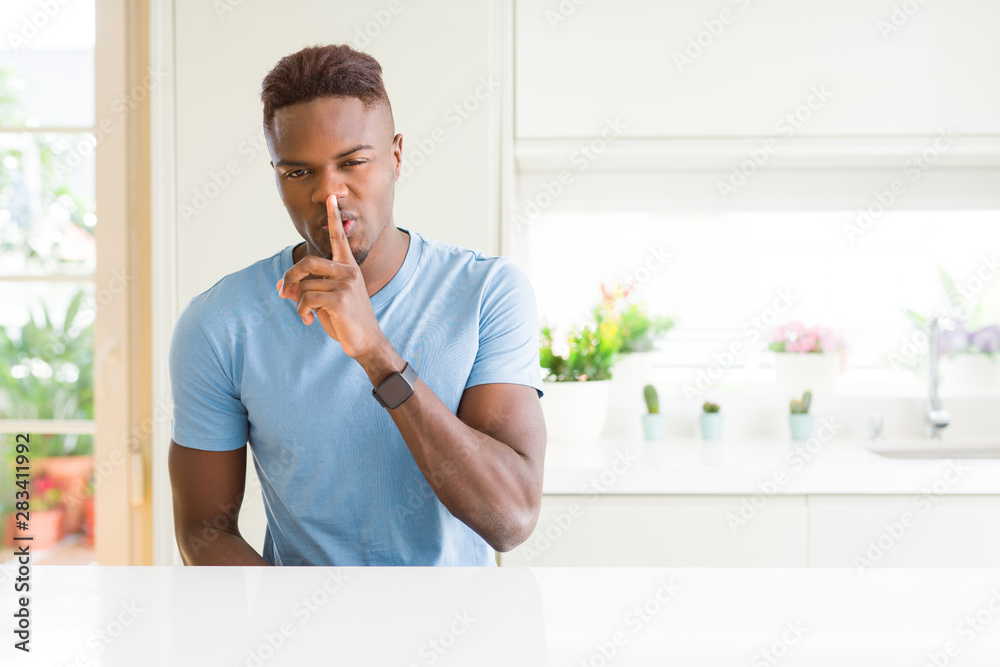 Handsome african american man wearing casual t-shirt at home asking to be quiet with finger on lips. Silence and secret concept. Handsome african american man wearing casual t-shirt at home asking to be quiet with finger on lips. Silence and secret concept.