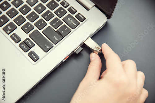 Woman's hand connects design aluminium pendrive to modern ultrabook. photo