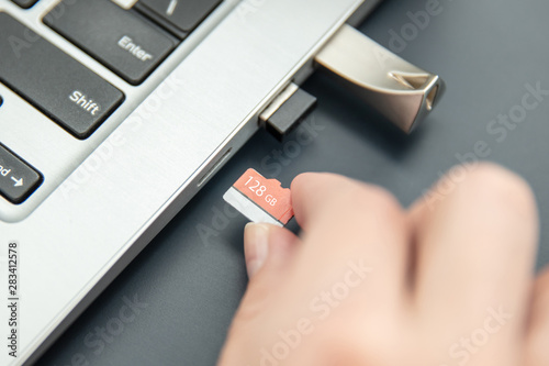 Woman's hand puts in fast, capacoius microSD card to the modern ultrabook.