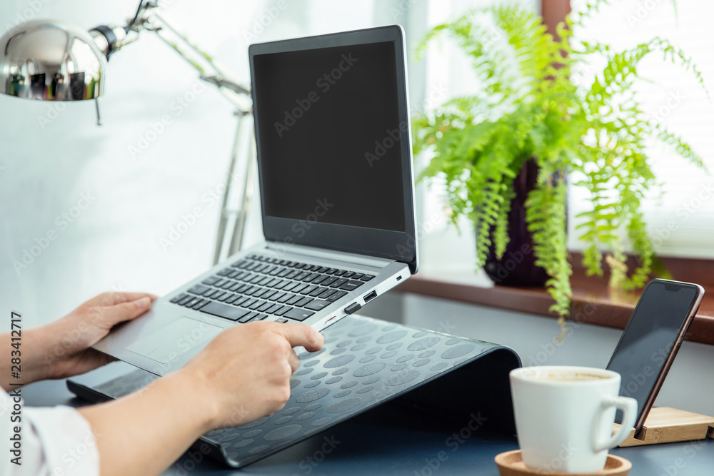 Fototapeta premium Woman puts her ultrabook to laptop's stand.