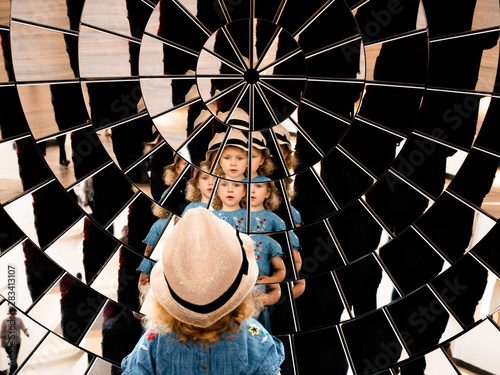 Girl's reflection in many mirrors arranged in a parabolic shape. Multiple points of view, multiple angles. Fragmented multi-faceted portrait. Mirror array. photo