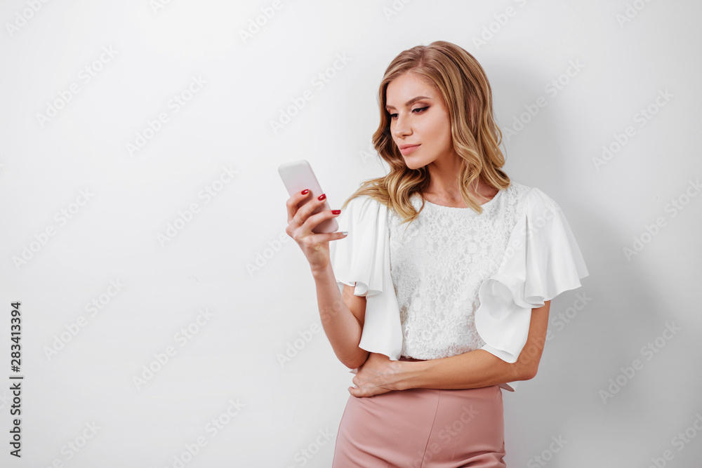 Portrait of a smiling casual woman holding smartphone over white background Portrait of a smiling casual woman holding smartphone over white background