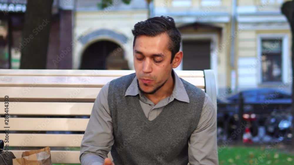 Lunch break. A young office worker eating lunch and drinking coffee outside in city. Sitting on a bench. Lunch break. A young office worker eating lunch and drinking coffee outside in city. Sitting on a bench.