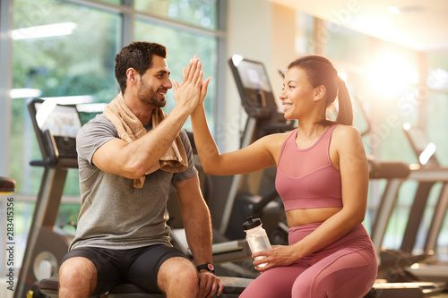 Portrait of beautiful sportive couple high five during workout in gym, copy space photo