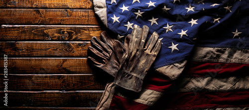 Old and worn work gloves on large American flag - Labor day background